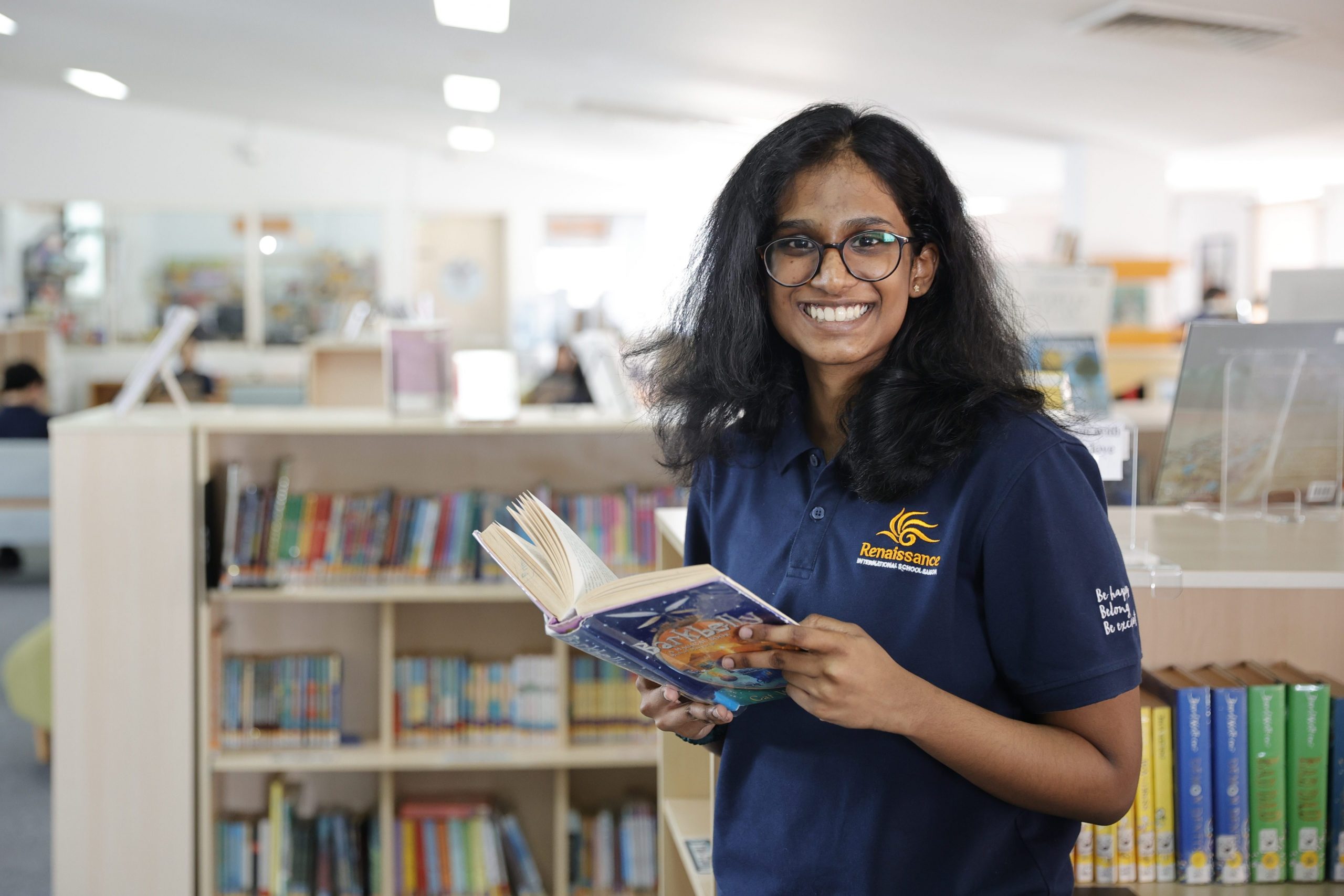 secondary student smiles holding a book in library